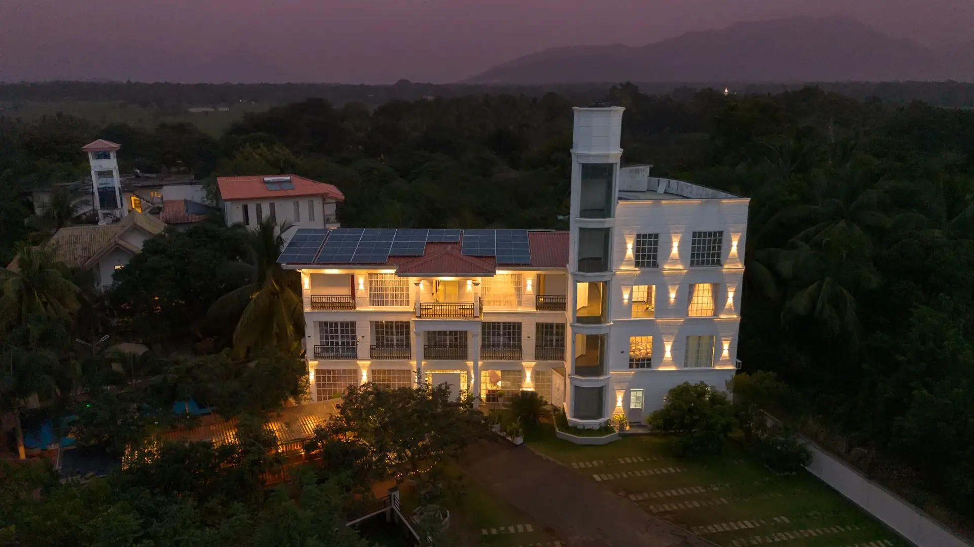 White Land City Hotel at dusk, surrounded by tropical greenery